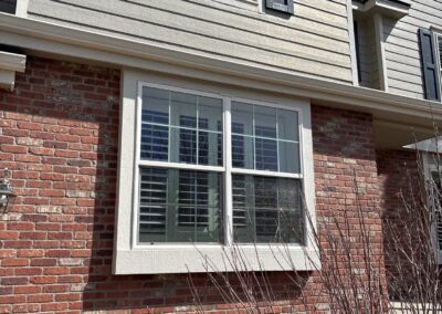 Windows on a tan house with brick viewed from the exterior